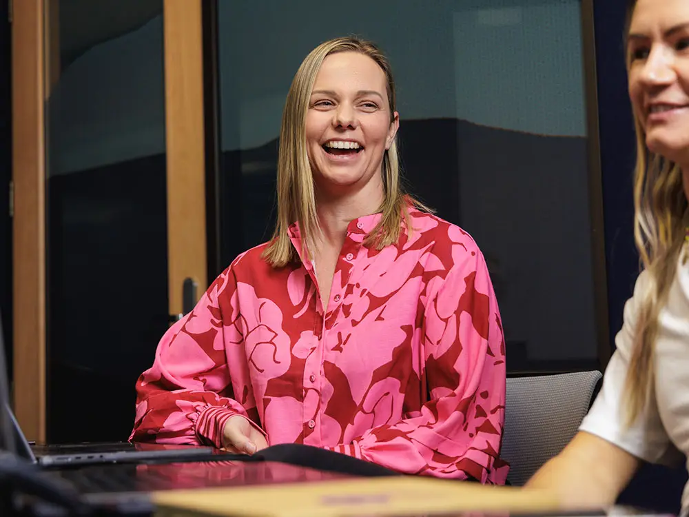 Smiling marketer in a pink top during a team discussion - Outsourced marketing services from a virtual marketing team in NZ