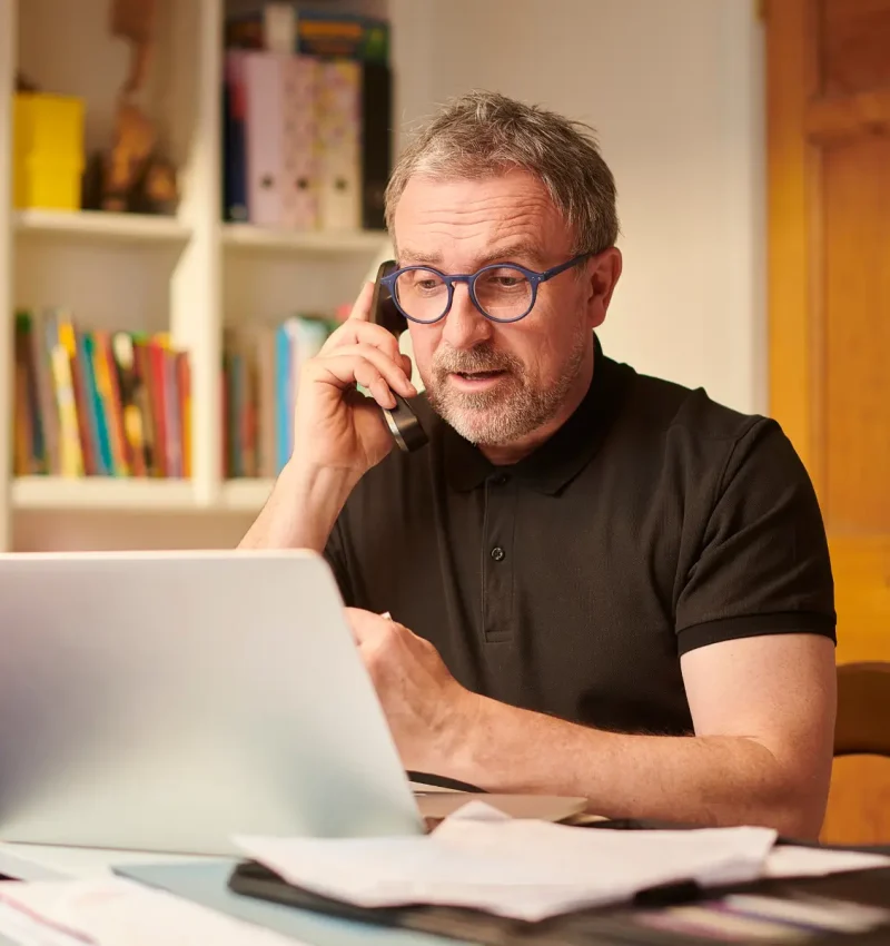 Small business owner on a phone call at his laptop - Marketing support for NZ small businesses
