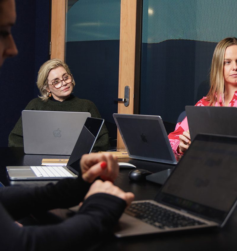 Marketing team working together on laptops around a table - Expert marketing strategy services in NZ